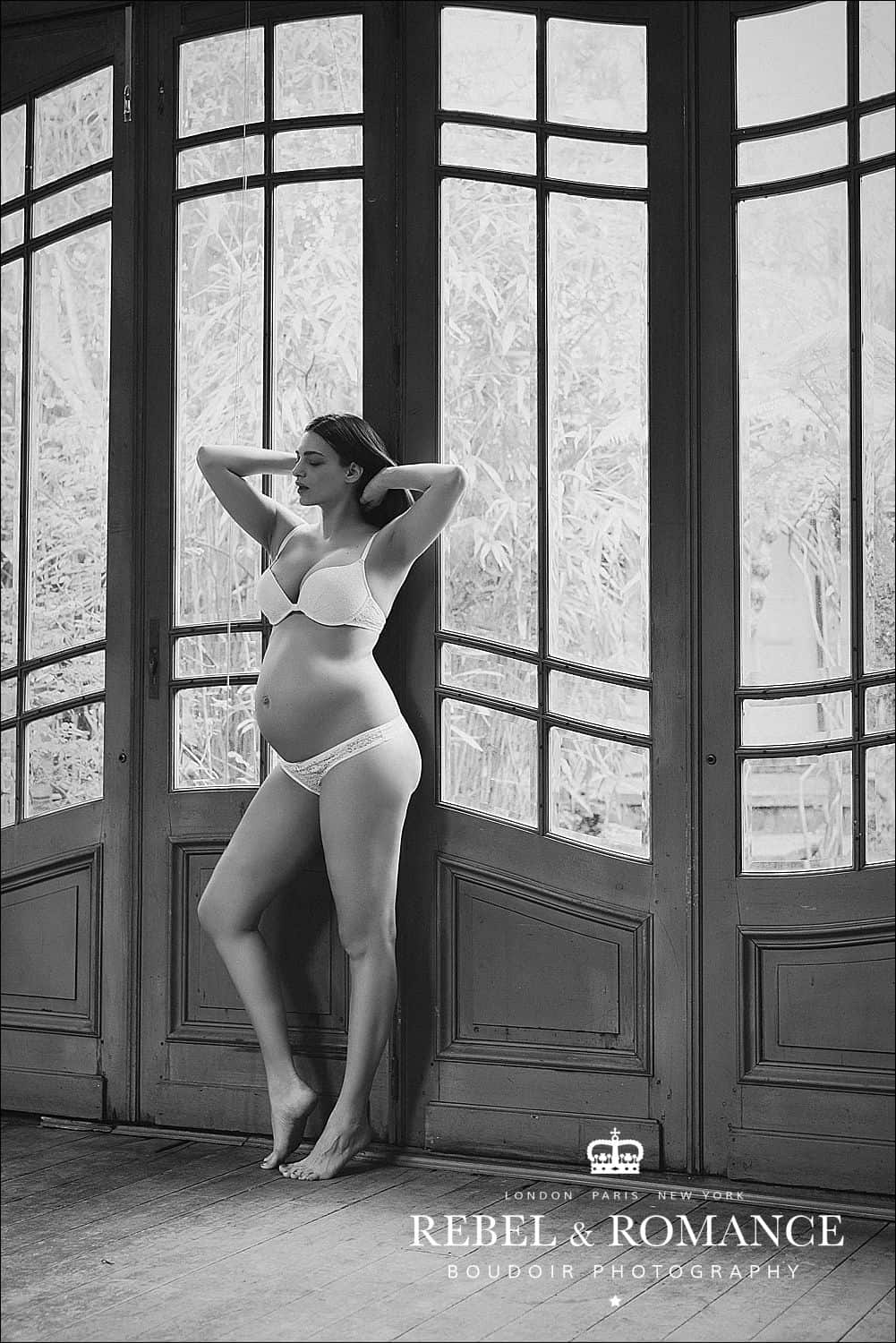 pregnant woman posing in lingerie in front of french doors