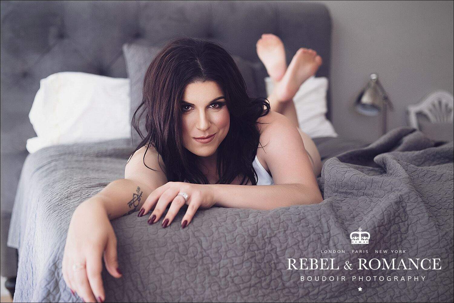 lifestyle boudoir image of brunette woman on grey bed
