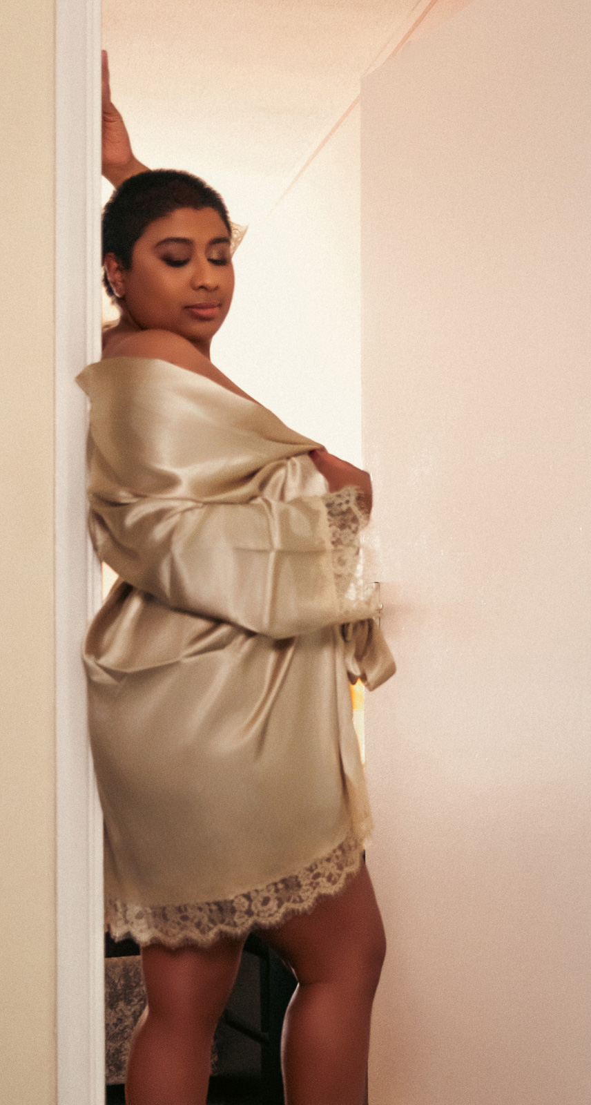 boudoir-photography-suffolk-british-south-asian-00014 Elegant boudoir portrait of a British South Asian woman wearing a champagne satin robe during a Suffolk boudoir photography session