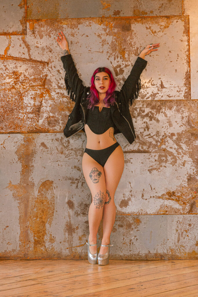 Warehouse boudoir photography London, warm toned metal rusted wall and fringe jacket