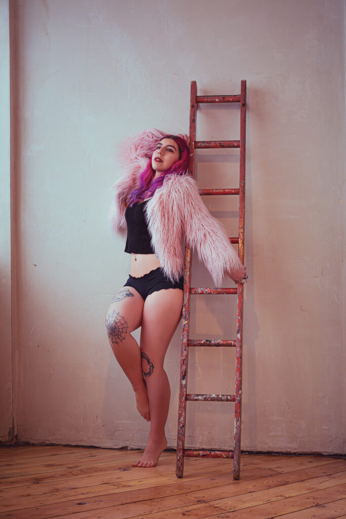 Editorial warehouse boudoir photography London, woman in pink fur, natural light and vintage ladder