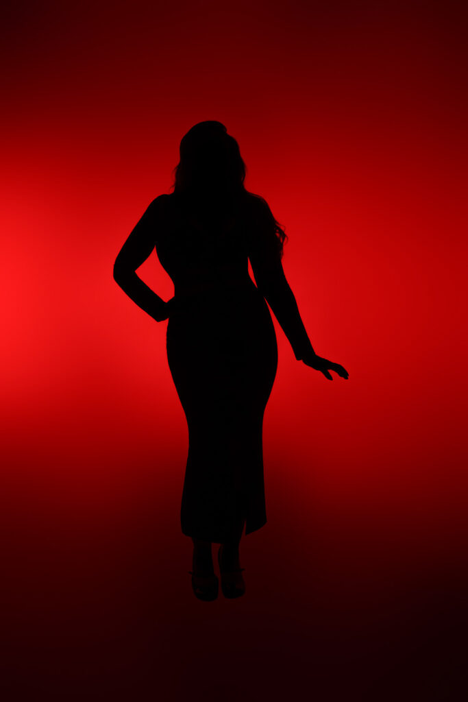 Curvy boudoir photoshoot silhouette against a red studio backdrop