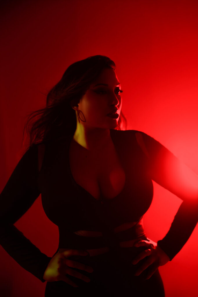 curvy woman, deep red lighting with light flare, black bodycon dress