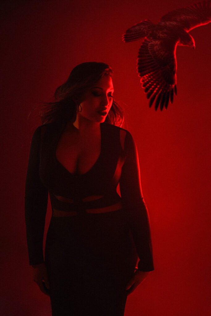 Boudoir photoshoot with a hawk in flight overhead, red backdrop, London studio
