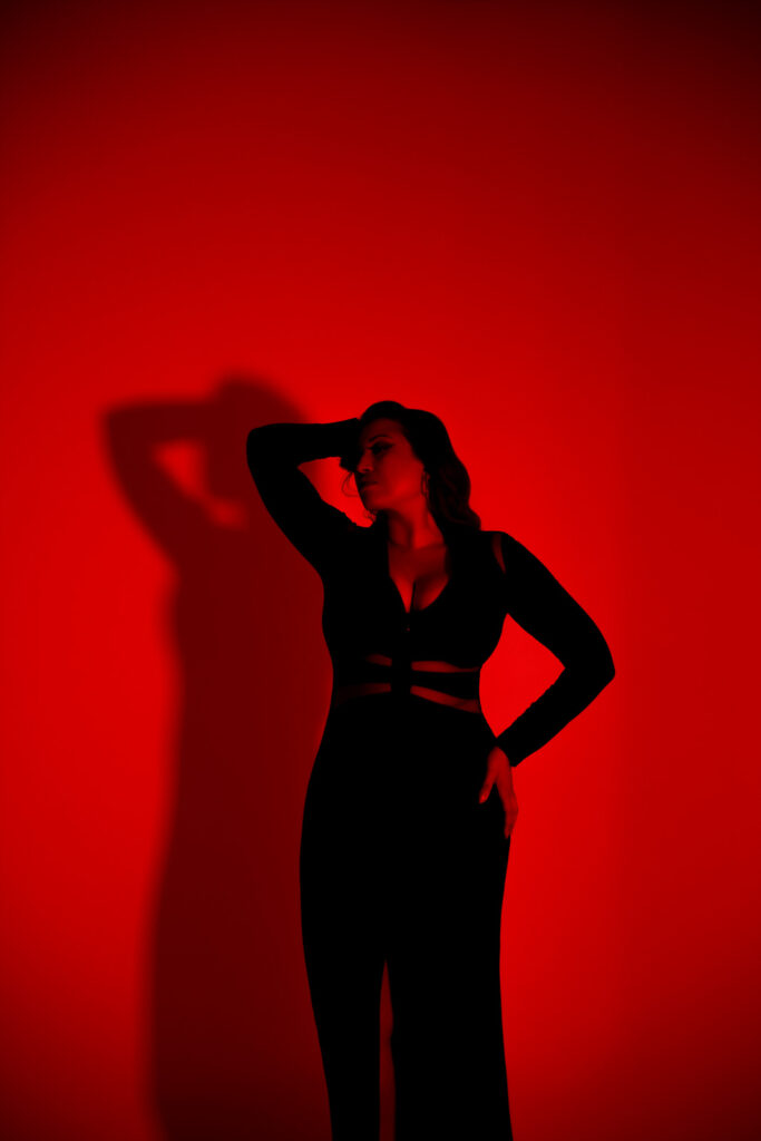 partial silhouette portrait with RBG studio lighting, black bodycon dress and dramatic pose