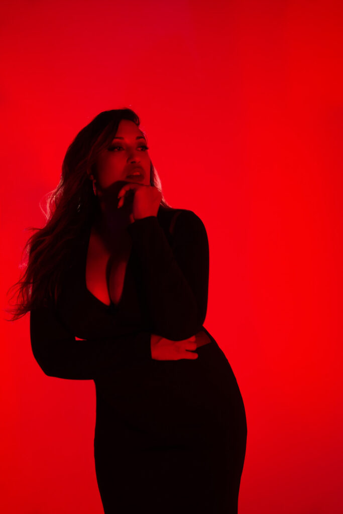 Close-up boudoir portrait with hand on chin, red lighting