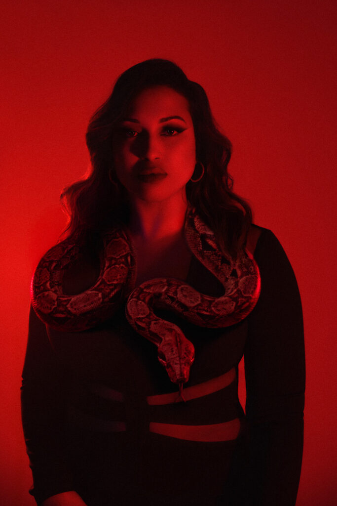 Portrait with a snake wrapped around the shoulders, red studio backdrop in London